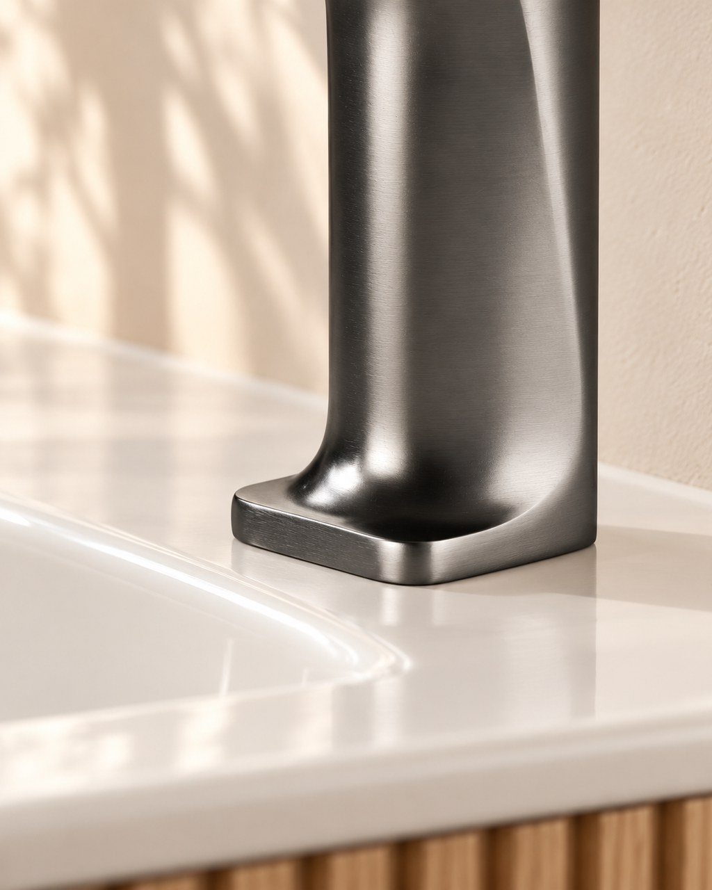 Socle du robinet SILVA gris brossé en contact avec le plan vasque en céramique blanche.