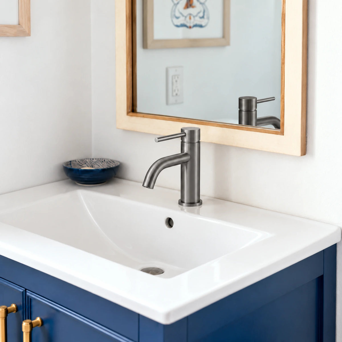 TILIO gris brossé OLVERTON en situation sur une vasque blanche et un meuble bleu profond, avec un miroir en bois.
